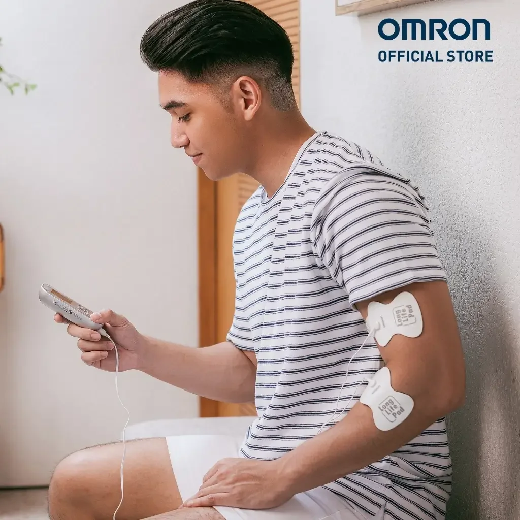 Nam thanh niên dán điện cực lên bắp tay tự điều trị thư giãn cơ với Omron HV-F021